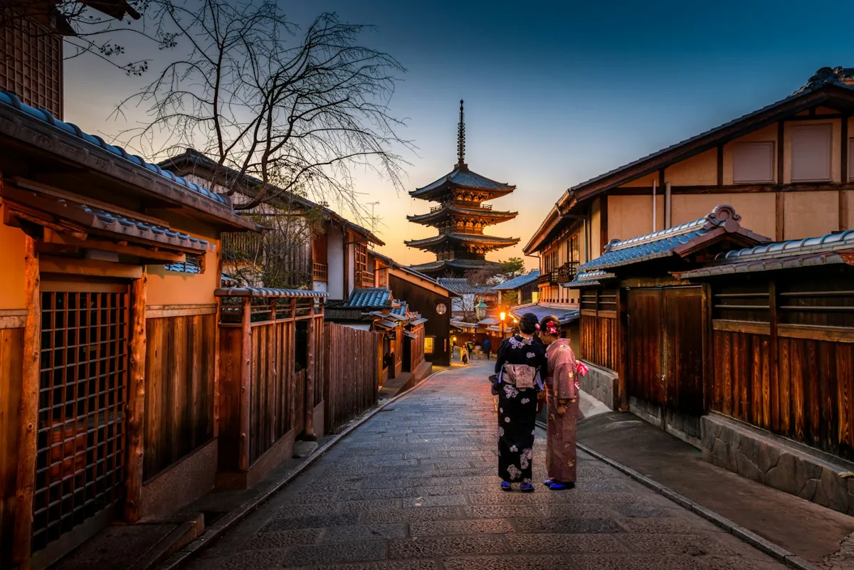A traditional Kyoto street leading towards a pagoda at dusk