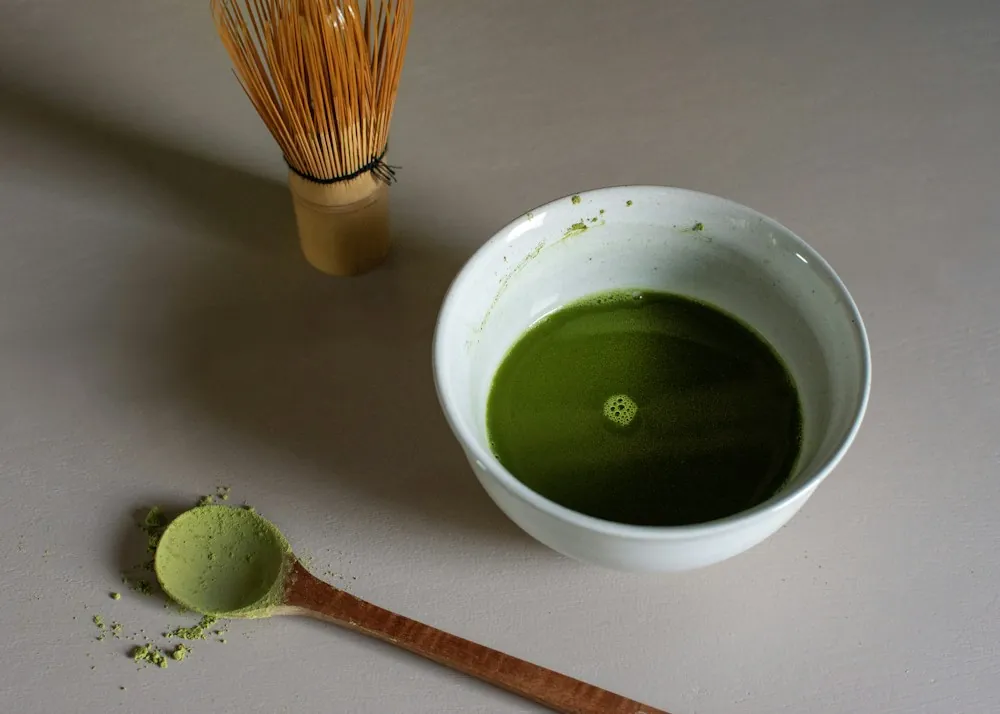 A bowl of matcha with a bamboo tea whisk